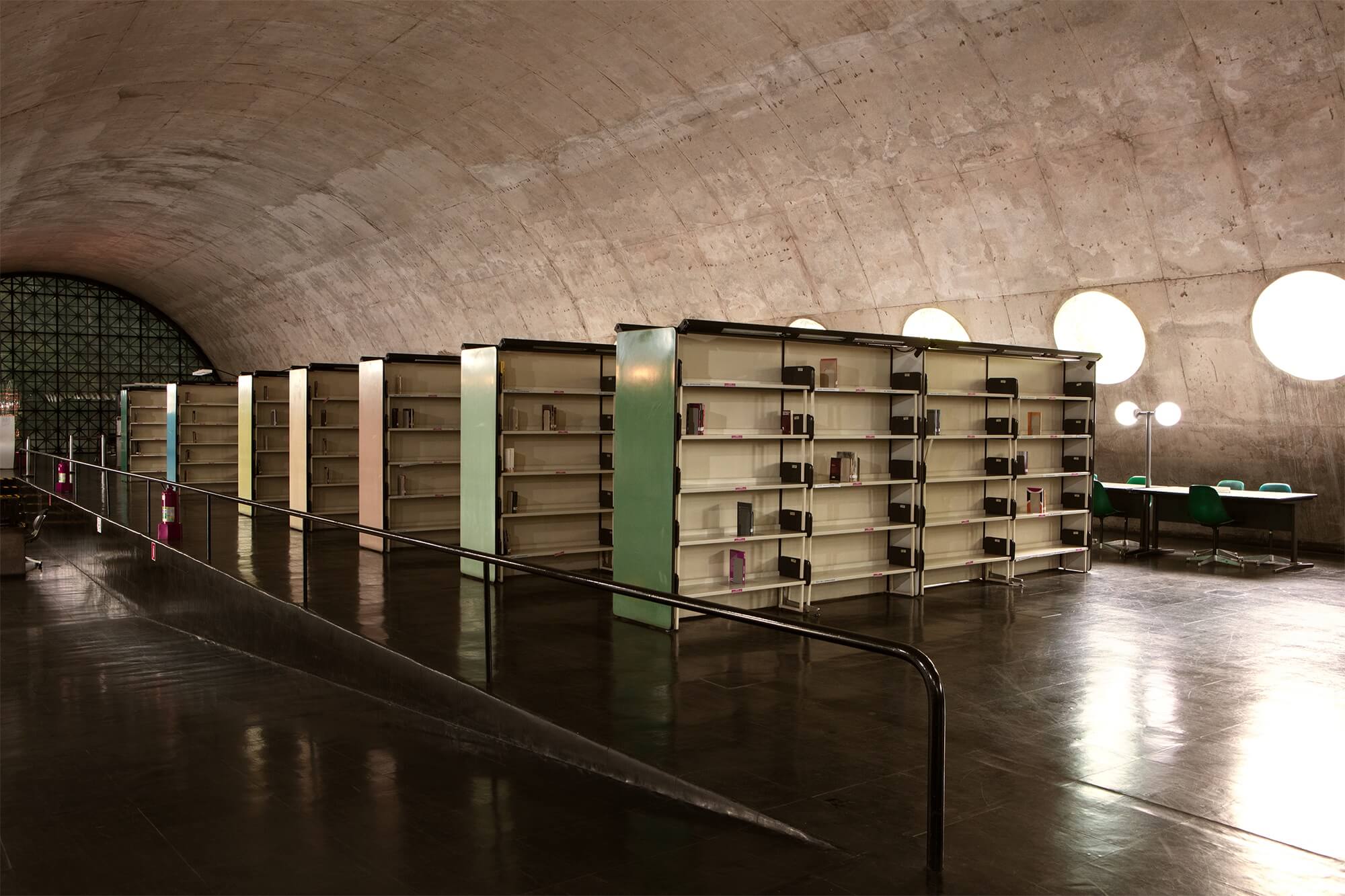 Nearly empty bookcases in a large, vaulted library 